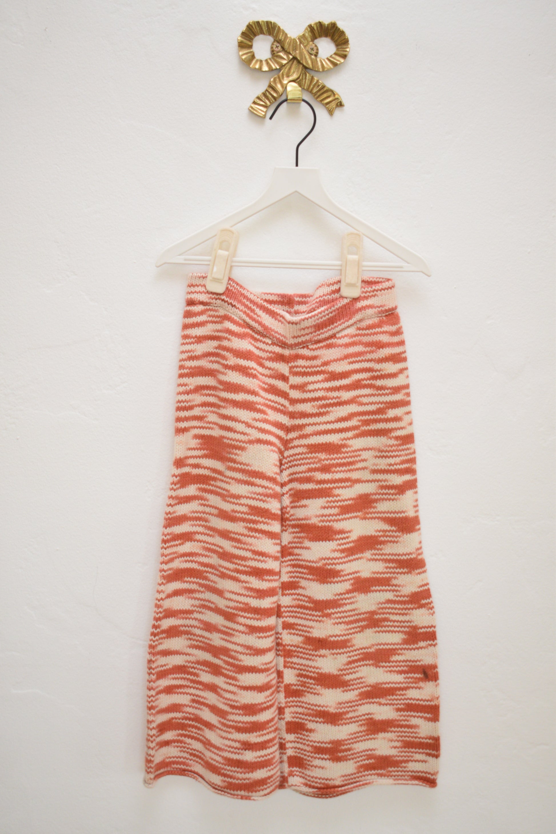 Misha & Puff red and cream marl knit kids pants, wide leg with elastic waist, size 4–5, on hanger against neutral wall.
