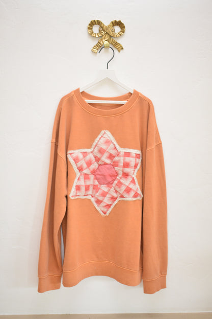 ASA upcycled orange cotton kids sweatshirt with quilted six-pointed star appliqué, size 10–12, on hanger against neutral wall.