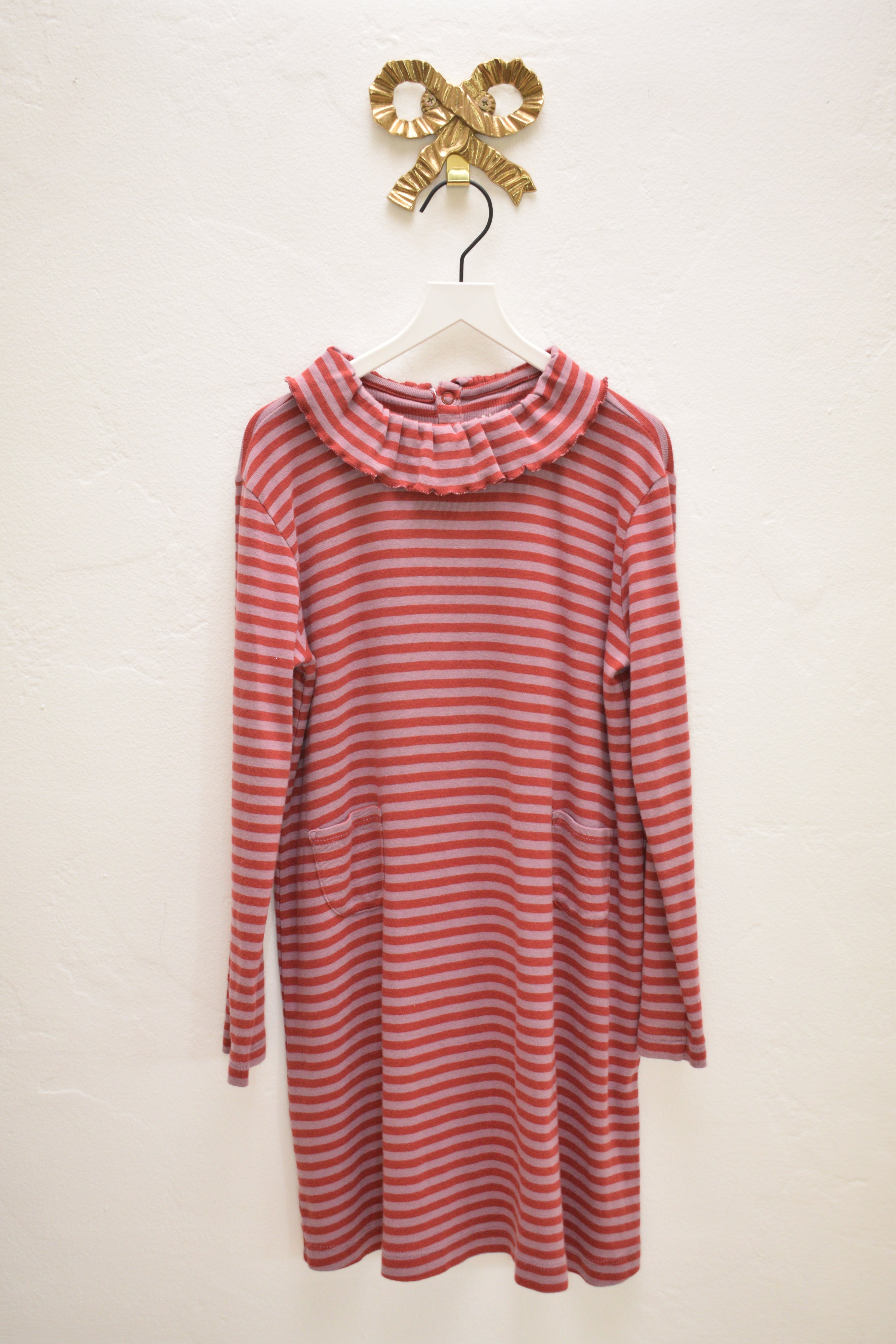 Misha & Puff raspberry and pink striped long-sleeve ruffle-collar dress, size 8–9 years, hanging on a white hanger against a neutral wall