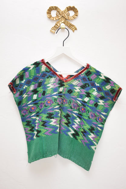 ASA one-of-a-kind woven tapestry top in forest green with multicolor zigzag and floral pattern, size 6–7 years, on a white hanger against a neutral wall.