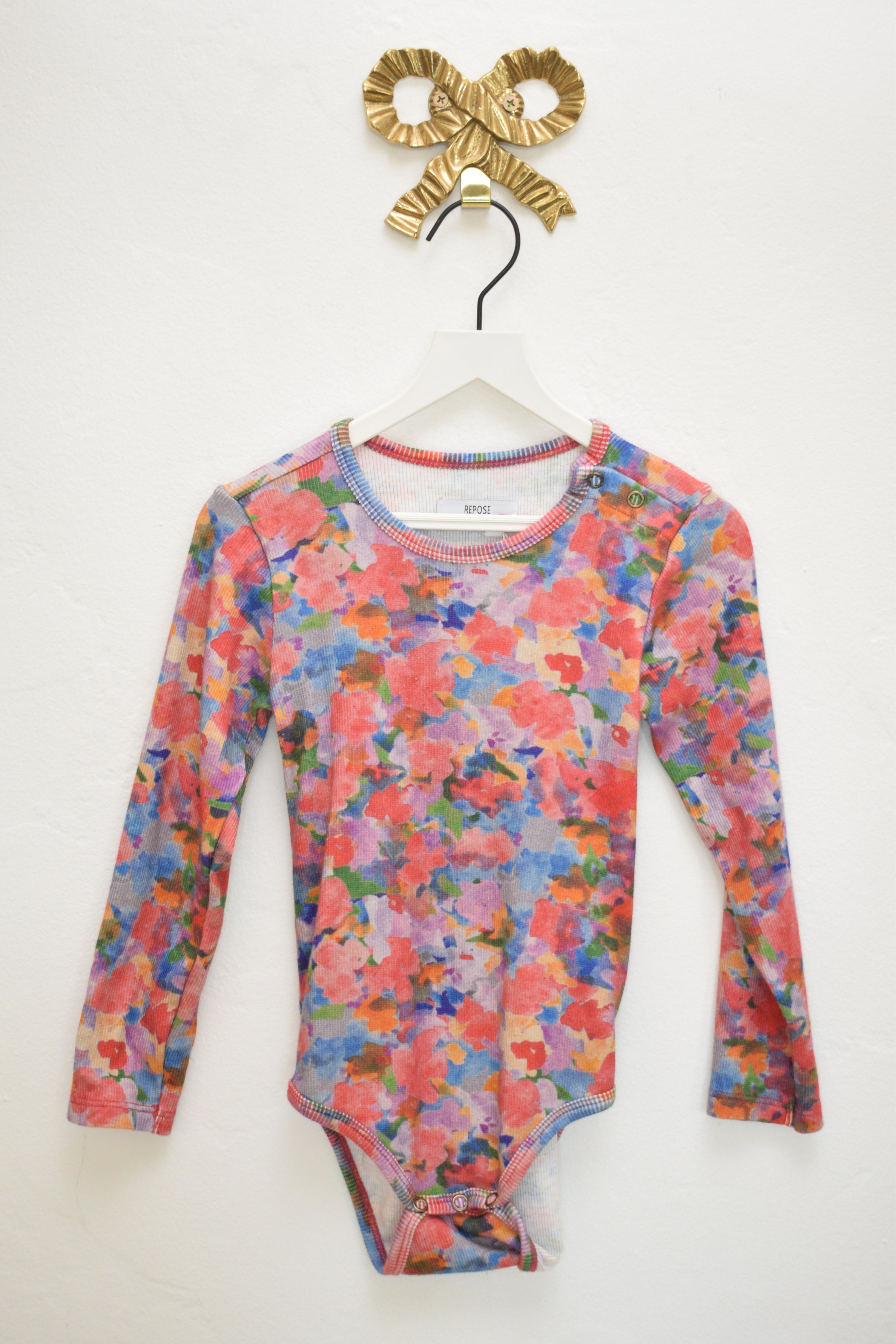 Floral-patterned long-sleeve shirt on a white background with a gold headband.